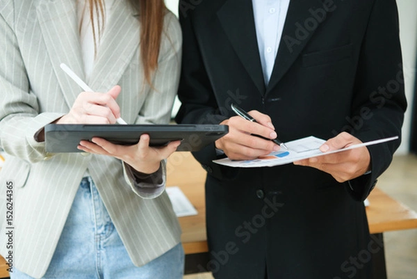 Obraz Two business people discuss financial strategy and collaborate with colleagues.