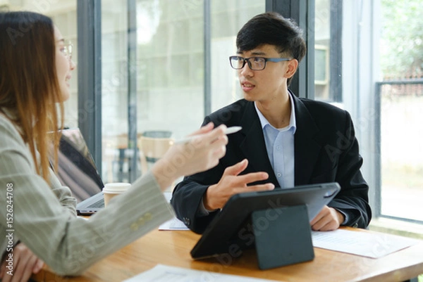 Obraz Two business people discuss financial strategy and collaborate with colleagues.