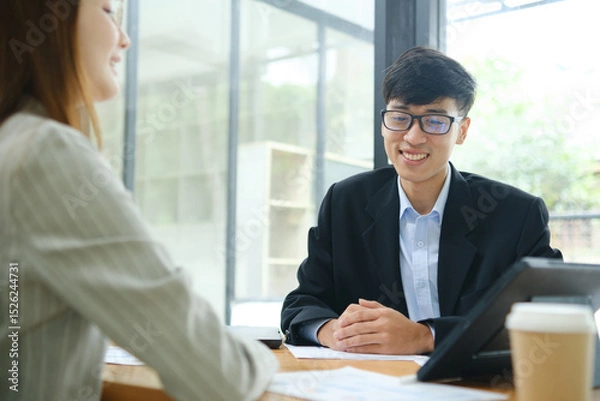 Obraz Two business people discuss financial strategy and collaborate with colleagues.