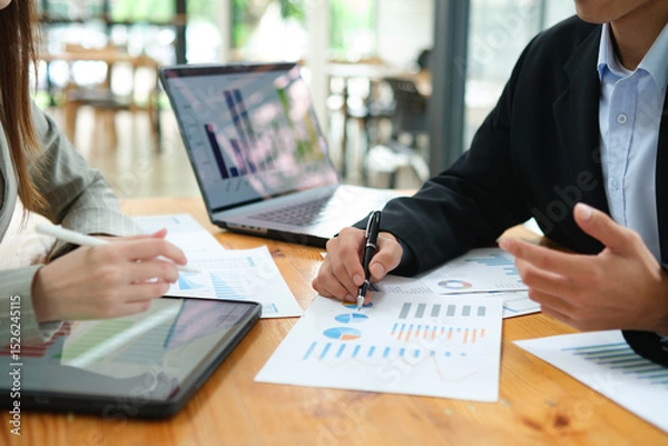 Obraz Two business people discuss financial strategy and collaborate with colleagues.