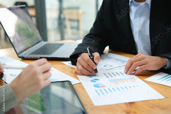 Obraz Two business people discuss financial strategy and collaborate with colleagues.