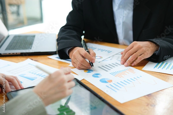 Obraz Two business people discuss financial strategy and collaborate with colleagues.