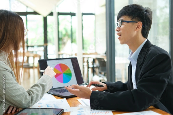 Obraz Two business people discuss financial strategy and collaborate with colleagues.