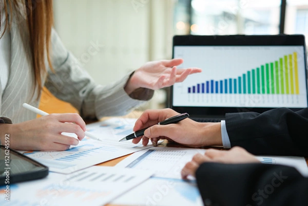 Obraz Two business people discuss financial strategy and collaborate with colleagues.