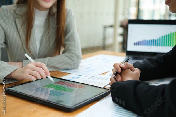 Obraz Two business people discuss financial strategy and collaborate with colleagues.