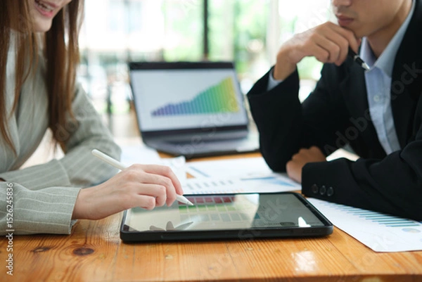 Obraz Two business people discuss financial strategy and collaborate with colleagues.