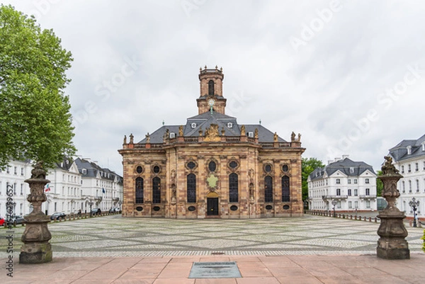 Obraz A large building Baroque church in the city of Saarbrucken in Germany with a clock tower and a small courtyard in front of it