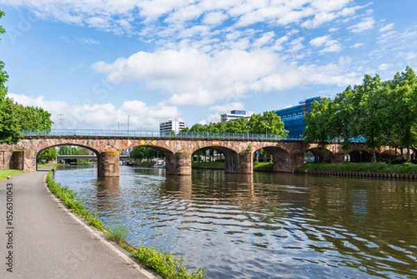 Obraz A old bridge spans a Saar river with a view of a city Saarbrucken Germany in the background