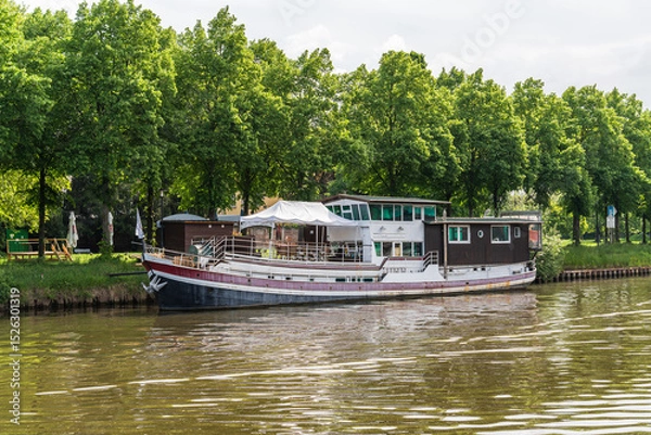 Obraz A boat is traveling down a Saar river near a Saarbrucken city in Germany