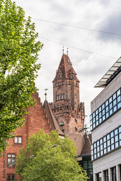Fototapeta A tall building with a clock tower and a tree in front of it in Saarbrucken Germany
