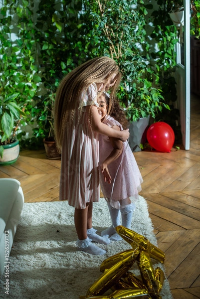 Obraz girls, Sisters joyfully embracing each other in a lush and cozy living space filled with warmth