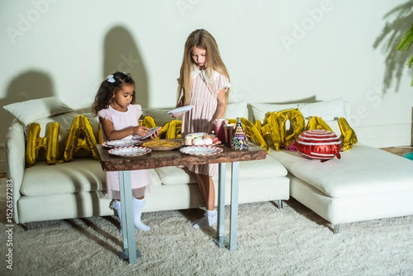 Obraz Two little girls are at a table set for a birthday party