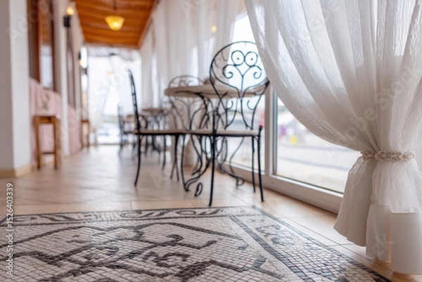 Fototapeta Elegant Mediterranean restaurant patio featuring light-filtering curtains, intricate tiled floor, and stylish wrought-iron furniture in a welcoming atmosphere