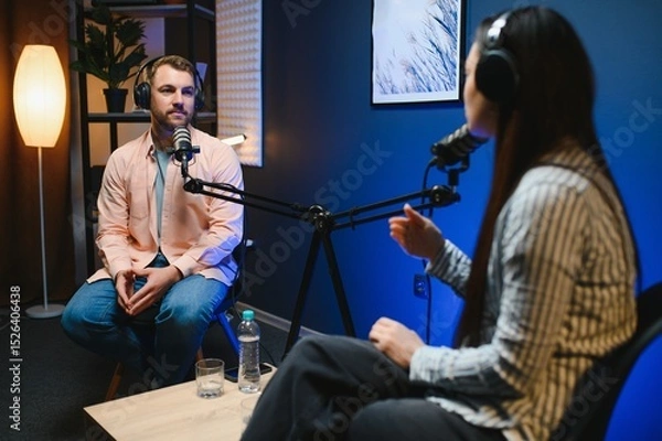 Fototapeta Side view of successful woman hosting podcast interviewing man while recording with professional microphones, copy space