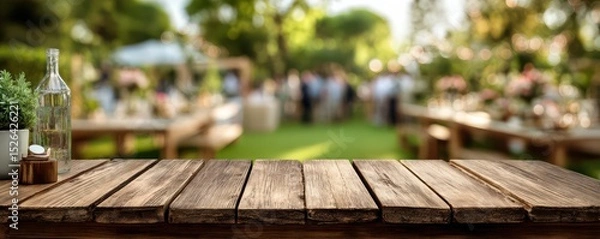Fototapeta Rustic wooden table foreground with blurred garden party setting in background, perfect for event planning and outdoor gatherings