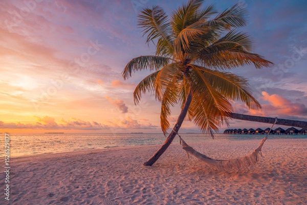 Fototapeta Closeup sunset view palm tree with hammock swing over golden sand sea. Romantic inspire carefree tropical landscape with vivid sky, perfect for summer vacation, relaxation, and dreamy beach background