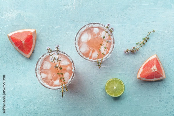 Fototapeta Salty Dog cocktail with fresh grapefruit juice, lime juice, and thyme, shot from the top with fruit slices