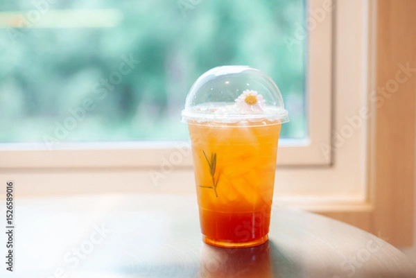 Fototapeta Plastic teacup on table in coffee shop. The interior of the shop is decorated in warm colors, modern and stylish. Relaxing queue concept.