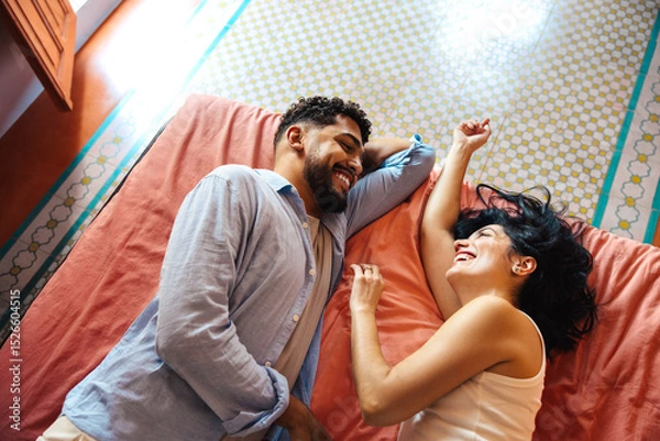 Fototapeta Smiling couple lying together on a bed during a relaxed morning