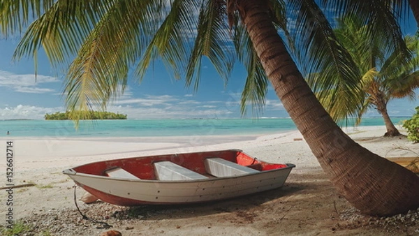 Obraz Small red and white boat resting on a pristine white sand beach under the shade of palm trees in Aitutaki, Cook Islands, with turquoise waters and a small island in the background