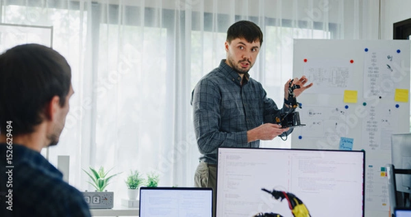 Obraz Team adult male engineer develop present AI robotics hand project at tech workspace. Artificial intelligence, collaboration support prototype development, robotic, debugging, machine learn, training.