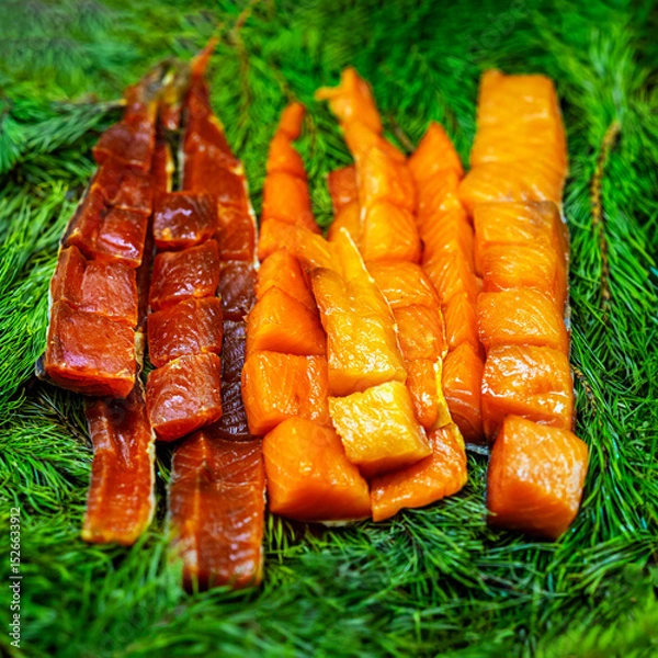 Fototapeta Slices of smoked fish arranged on fir branches for rustic food presentation. Concept of smoked fish, traditional cuisine, freshness and gourmet delicacy. Healthy eating and fish market concept