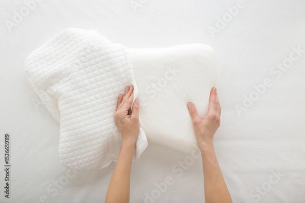 Fototapeta Young adult woman hands changing white cotton cover on soft memory foam pillow on mattress background. Closeup. Point of view shot. Top down view.