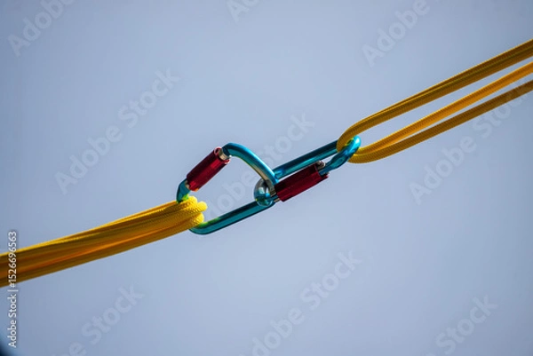 Fototapeta A yellow and blue rope with a blue and red clip attached to it