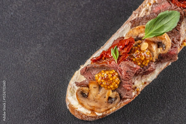 Obraz Gourmet open-faced sandwich with seared beef, mushrooms, sun-dried tomatoes, mustard seeds, and fresh basil on crusty bread