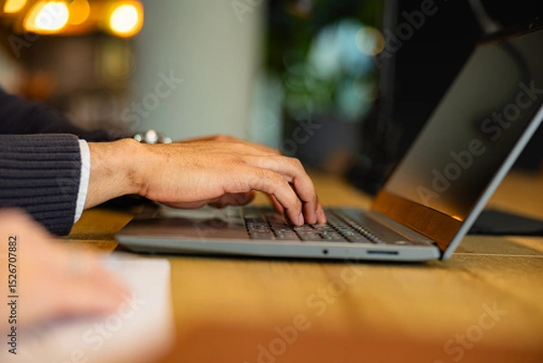 Fototapeta Close up of male hands typing on a laptop keyboard, focused on work tasks in a modern office environment, showcasing productivity and efficiency