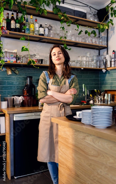 Obraz Portrait of female barista standing in her coffee shop behind the counter.