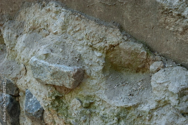 Fototapeta Concrete wall with granite pieces mostly crumbled. Cement between stones is cracked and worn, showing signs of age and decay.