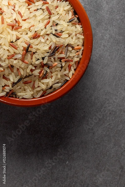 Fototapeta Earthenware bowl full of long, red, wild rice on a kitchen countertop in a zenithal photograph