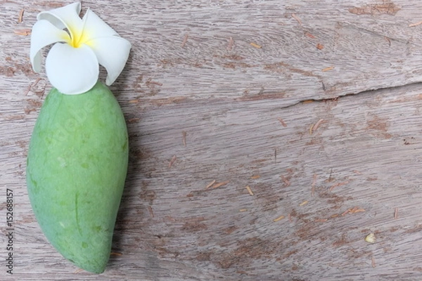 Fototapeta Green mango on the table with wooden background