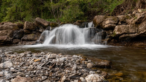 Obraz Mountain stream waterfall in Belianske Tatras, Slovakia. Scenic nature with rocks, clear water, forest background. Long exposure landscape perfect for travel and nature themes.