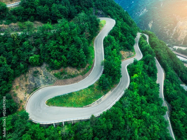 Obraz Aerial view of mountain curvy road and green forest in summer. Dolomites, Italy. Top drone view of winding road on mountain pass, trees in spring. Road through the woods. Moody landscape with roadway
