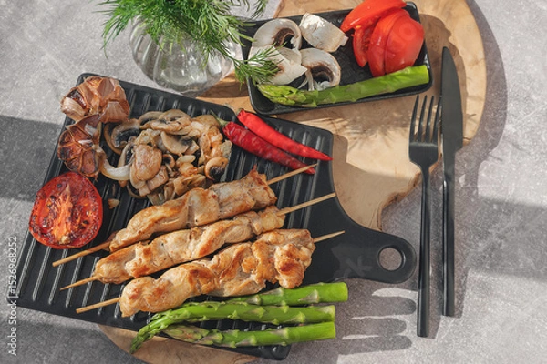 Fototapeta Barbecue on bamboo sticks. Grilled chicken kebab with mushrooms, asparagus and tomato. Red hot kebab.