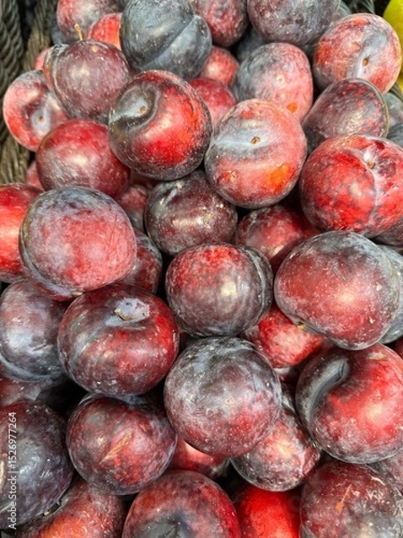 Obraz vibrant pile of dark red and purple plums with natural wax coating, displayed for sale.