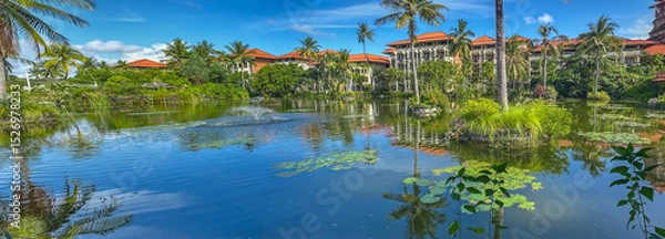 Obraz Landscape with Ayodya Resort Bali - Indonesia, featuring a large pond with palm trees and traditional Balinese architecture