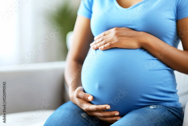 Fototapeta Close up of expecting mother s hands gently cradling her baby bump with soft blur
