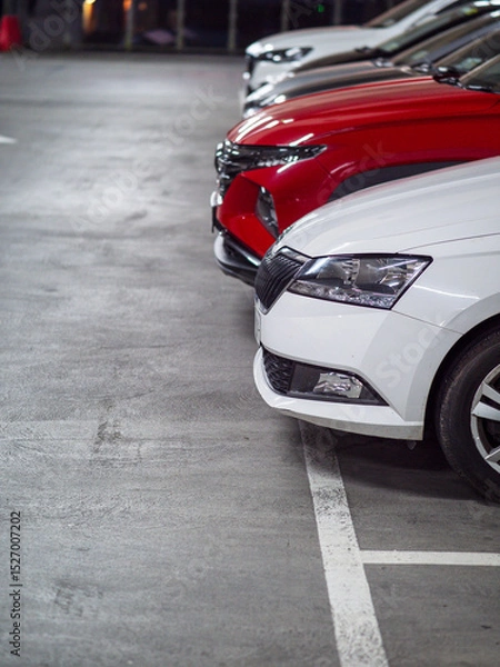 Fototapeta Raw of cars in an underground car park with white and red color vehicle in front. Selective focus. City over crowing problem.