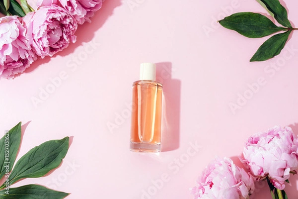 Fototapeta Perfume bottle and pink peony flowers on light pink background with shadows. Top view, flat lay