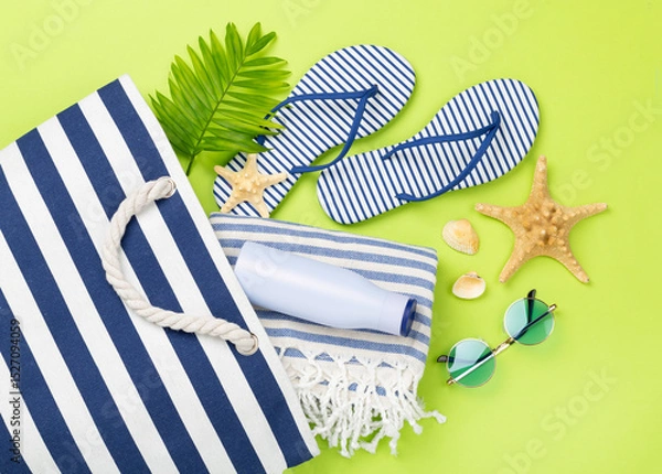 Fototapeta Blue beach bag with summer accessories on color background, top view