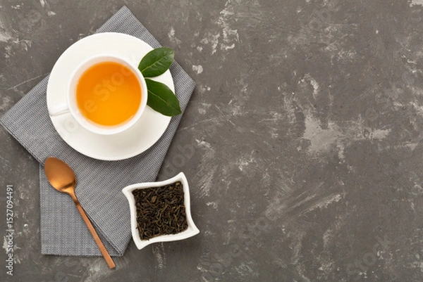 Fototapeta Cup of tea with dry and fresh leaves on concrete background, top view