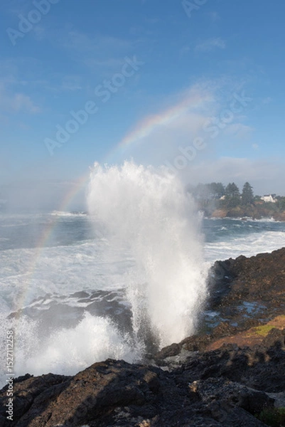 Fototapeta A beautiful water spout through the rocks with a rainbow through the spray