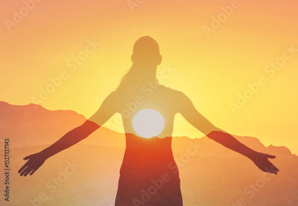Fototapeta Woman enjoying the warm sunshine feeling joyful with open arms standing in a field	
