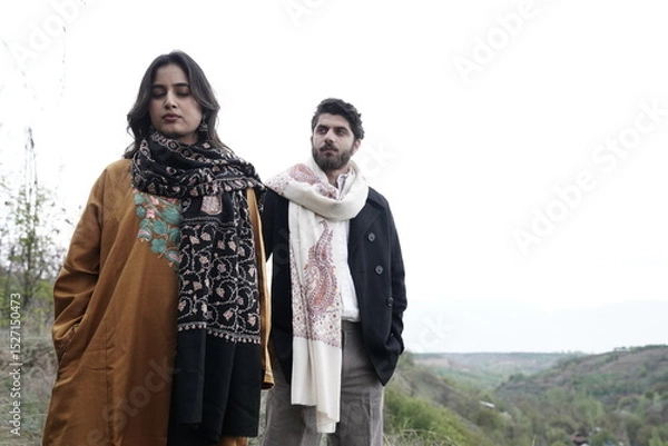 Fototapeta A couple posing in traditional Kashmiri attire, adorned in handwoven shawls and embroidered pherans, showcasing the rich heritage and artistry of Kaar Kash in a styled fashion shoot.


