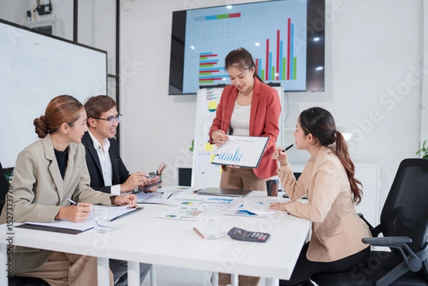 Fototapeta Group of Asian businesspeople sit at a table with graph paper in a meeting.