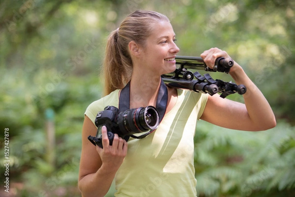 Fototapeta female photographer in the countryside with a camera and tripod