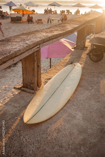 Fototapeta Beige surfboard in the sun. Surfer shortboard on a concrete background in the rays of the setting sun. The concept of sport and surfing on the islands